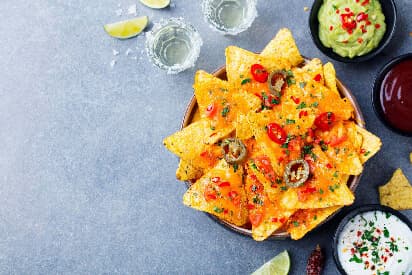 A Tray Of Mexican Nachos With Dips